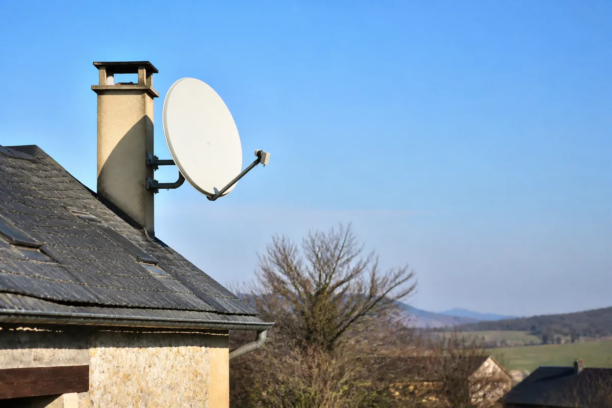 Antenne parabolique sur toit en zone rurale recevant des signaux TV par satellite